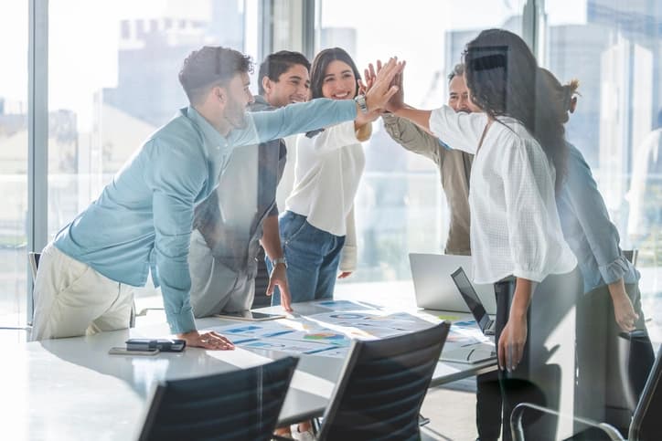 Business team celebrating success with high-five during strategy planning session in modern office