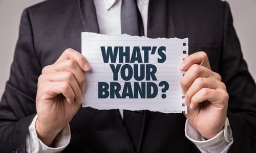 Business professional holding sign asking 'What's Your Brand?' for brand positioning strategy