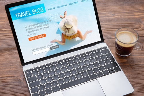 Laptop displaying travel blog website with coffee cup, showing professional blog content management